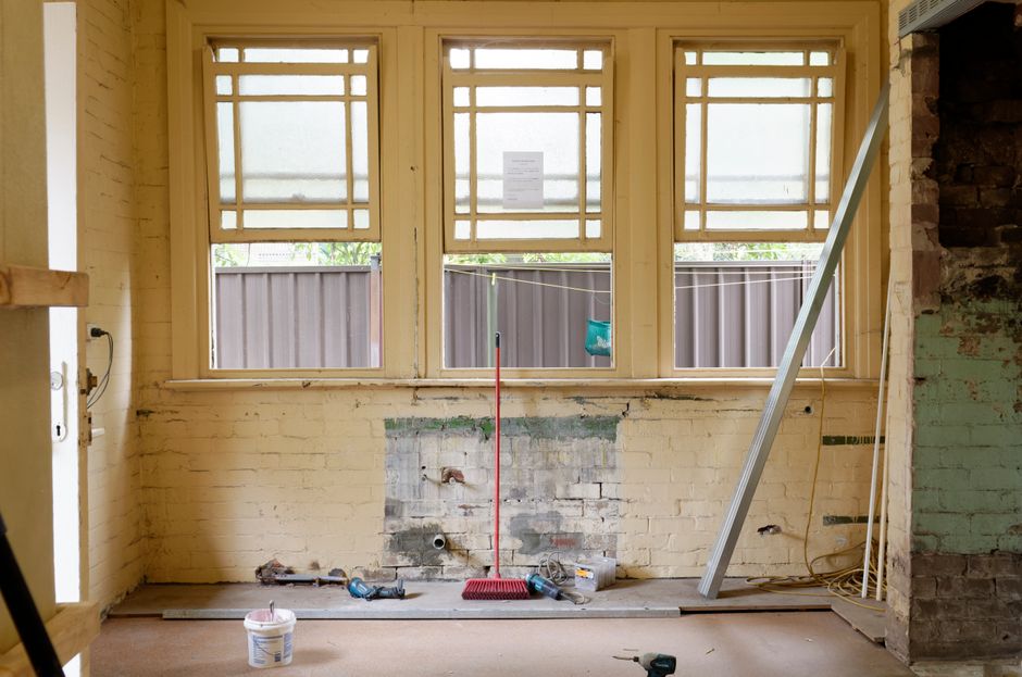 The image depicts an interior room during a deep cleaning process, with a focus on surface sanitisation. The room has a wooden floor that appears to be in the midst of cleaning, with some areas showin